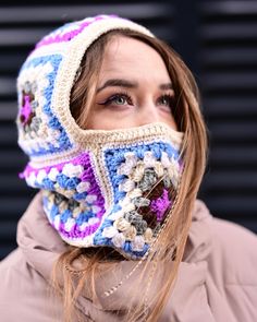 a woman wearing a crocheted hat with a scarf around her face and covering her eyes