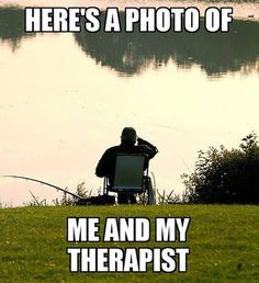 a man sitting in a chair on top of a field next to a body of water