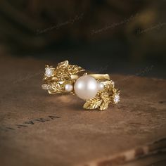 a close up of a ring on top of a book with leaves and pearls in it