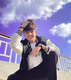 a young man is sitting on the steps with his hand in his hair and smiling