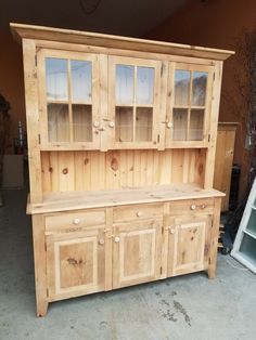 a wooden hutch with glass doors and drawers on it's sides in a garage