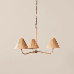 three light chandelier with beige shades hanging from the ceiling in an empty room