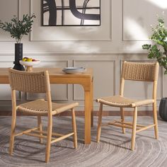 two wicker chairs sitting at a wooden table in front of a painting on the wall