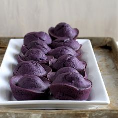 some purple cupcakes are on a white plate