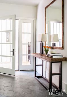 an entry way with a mirror, table and lamp