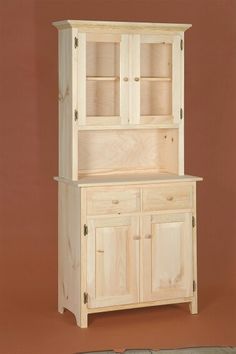 a wooden hutch with two doors and cupboards on one side, in front of a brown wall