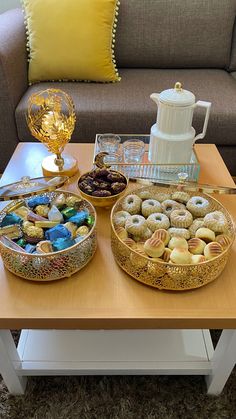 two trays filled with donuts sitting on top of a table next to a couch