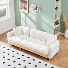 a white couch sitting on top of a hard wood floor next to a green wall