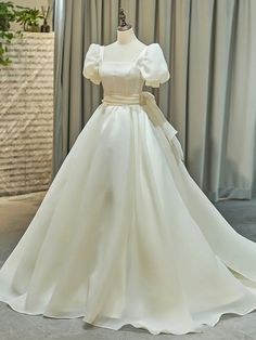 a white wedding dress on display in front of curtains