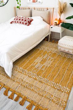 a white bed sitting next to a yellow rug