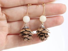 a pair of earrings with pine cones hanging from them