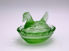 a green glass bowl sitting on top of a white table