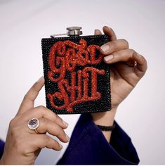 a woman holding up a black and red purse