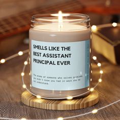 a candle that says smells like the best assistant principals ever on it with lights around it