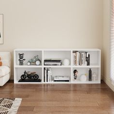 a living room filled with furniture and a white book shelf on top of a hard wood floor