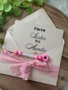 an envelope with a pink ribbon tied around it and a name tag attached to the front