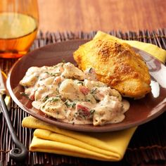 a plate topped with chicken and gravy next to a glass of orange juice