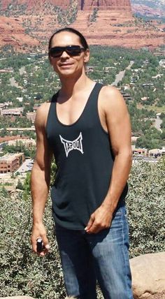 a man standing on top of a hill with mountains in the background