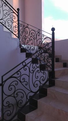 an iron stair railing on the side of a building with white walls and black handrails