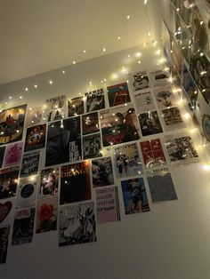 a wall covered in pictures and lights with string lights hanging from the ceiling above it