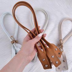 a person holding three different colored leather bags in one hand and the other is tied up with twine