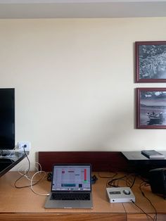 an open laptop computer sitting on top of a wooden desk next to a tv monitor