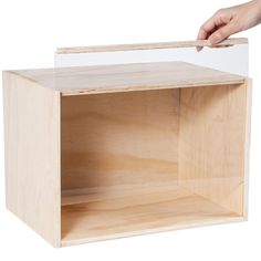 a person is holding a clear plastic box over a wooden shelf that's been built into the wall