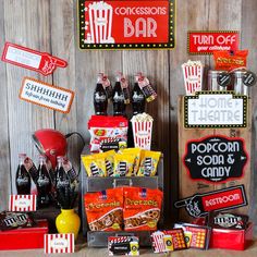 an assortment of snacks and candy displayed on a wooden table in front of a sign that says concession bar