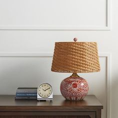 a table with a lamp, clock and books on it