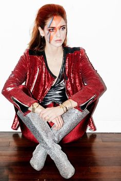 a woman sitting on top of a wooden floor with her legs crossed and painted red