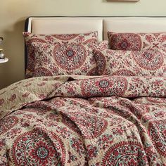 a bed with red and blue bedspread in a bedroom next to a lamp