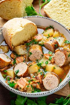 a bowl filled with meat and potatoes next to bread