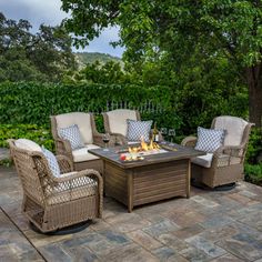 a fire pit sitting on top of a patio next to chairs and tables covered in pillows