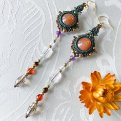 two pieces of jewelry sitting on top of a table next to a flower and brooche