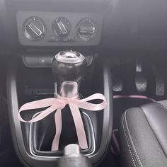 a pink ribbon tied around the center console of a car