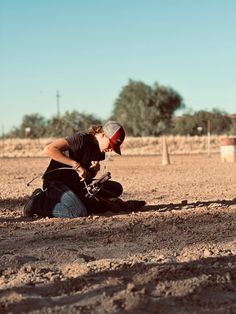 a man kneeling down in the dirt next to a horse