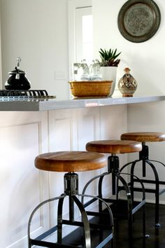 three wooden stools sitting in front of a counter