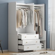 a white wardrobe with drawers and clothes hanging on it's doors, in a blue room