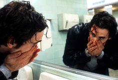 two men are looking in the mirror and covering their faces with their hands as they look at each other