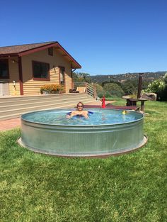 a man is swimming in an above ground pool on the lawn with his feet up