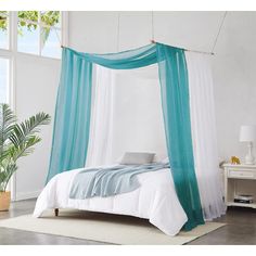 a bed with white and blue drapes hanging from it's sides in a bedroom