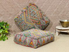 an upholstered chair and footstool in front of a patterned wall