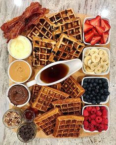 waffles, fruit, and other foods are arranged on a cutting board to be eaten