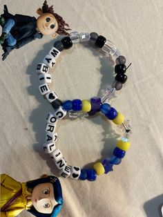 two bracelets with beads and plastic figures on top of white cloth covered tablecloth