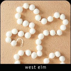 a white beaded necklace and earring laying on the ground next to each other