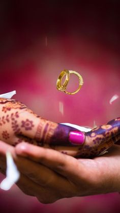 two hands with henna and wedding rings on them