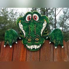 a green and white alligator head on top of a wooden fence