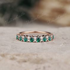 a wedding band with emeralds and white diamonds on the top, set in 18k rose gold