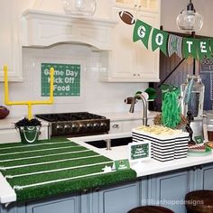 a football themed party with green and white decorations on the kitchen counter, bar stools