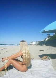 a woman sitting on top of a sandy beach